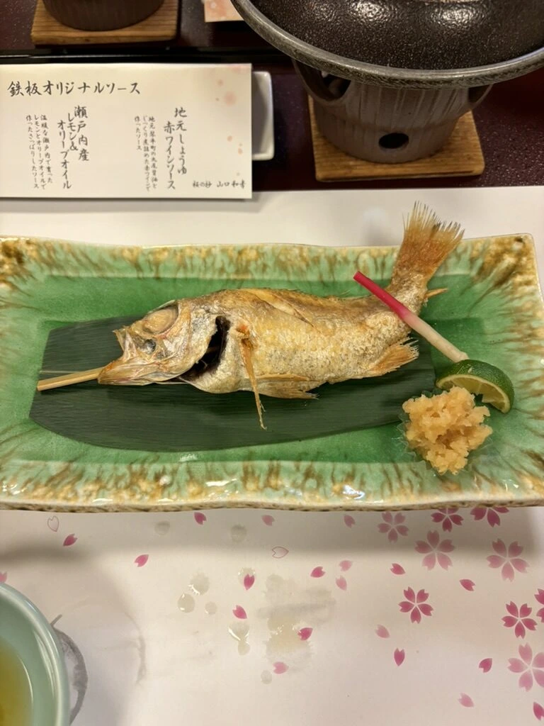 琴平グランドホテル 桜の抄の夕食。緑の皿にのった焼き魚と「鉄板オリジナルソース」のお品書き