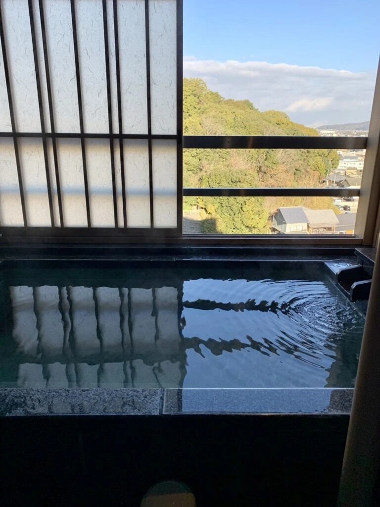 琴平グランドホテル 桜の抄の客室の窓際にある石張りの半露天風呂と、外の山の緑