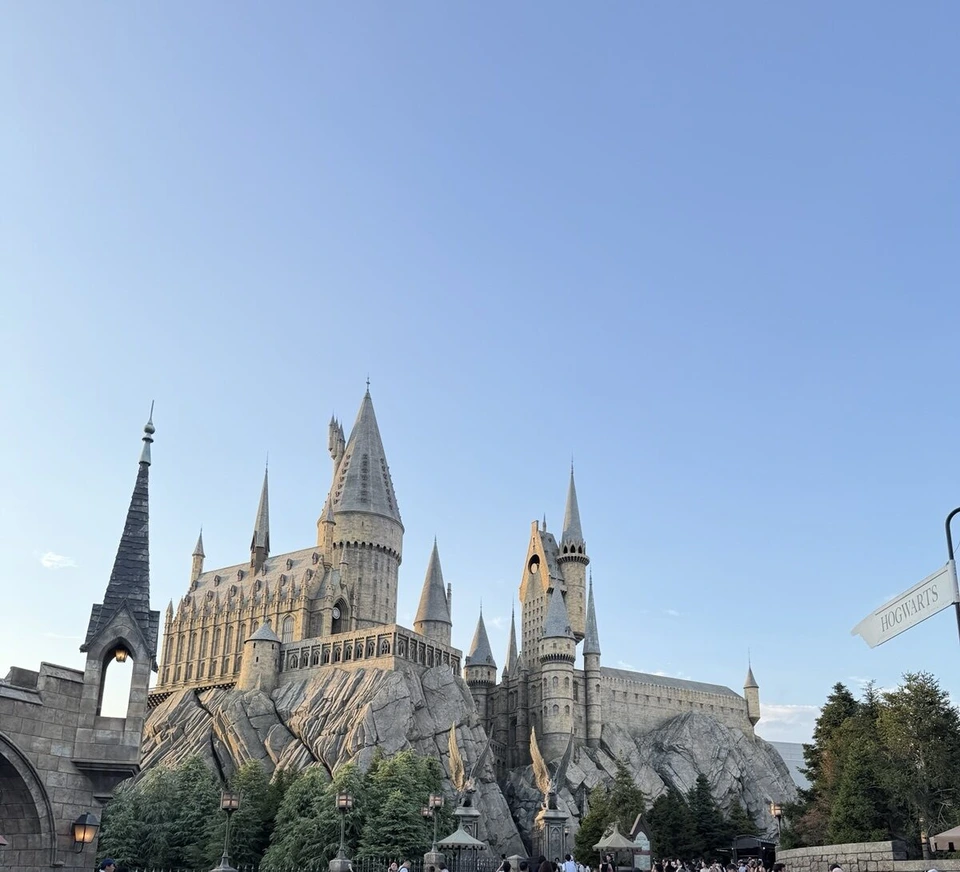 夕方の光が当たったホグワーツ城。HOGWARTSの道しるべと青い空