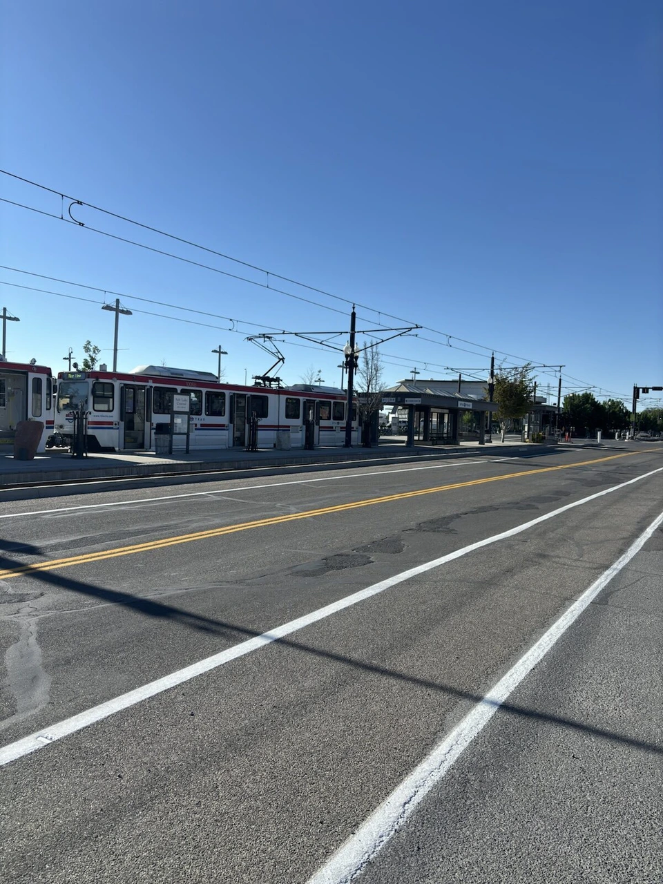 ソルトレイクシティ近郊、架線の張られたTRAXの線路沿いの道路と遠くの駅