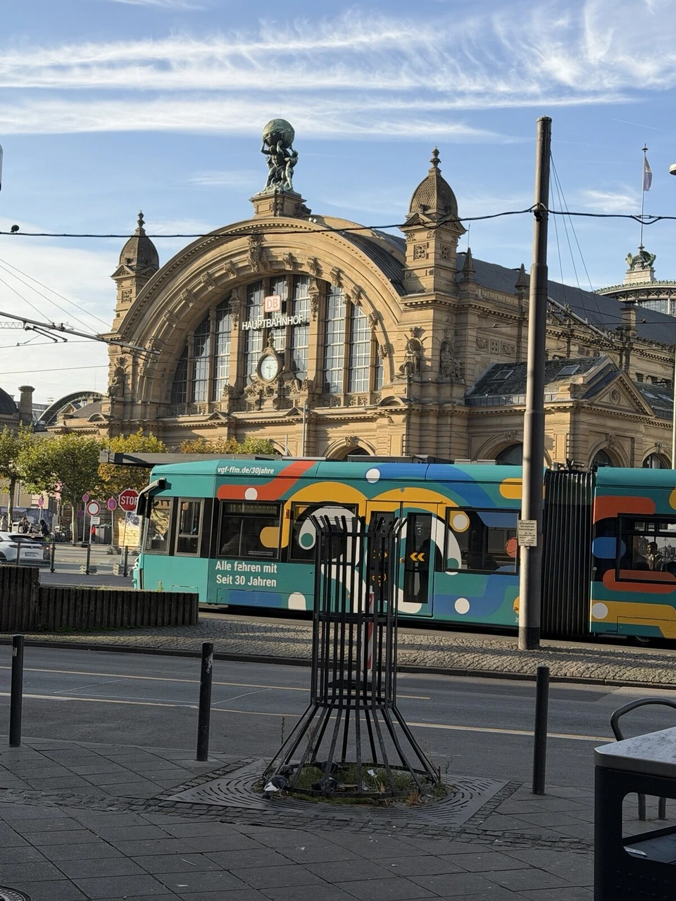 青空の下のフランクフルト中央駅の駅舎と、前を走る路面電車