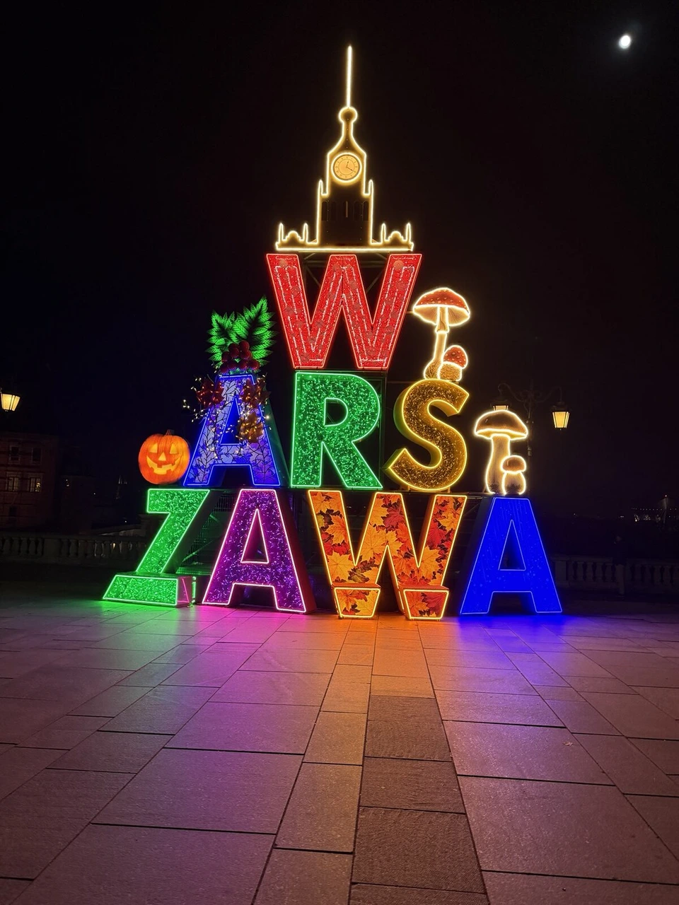 夜の王宮広場で光るカラフルなWARSZAWAの文字