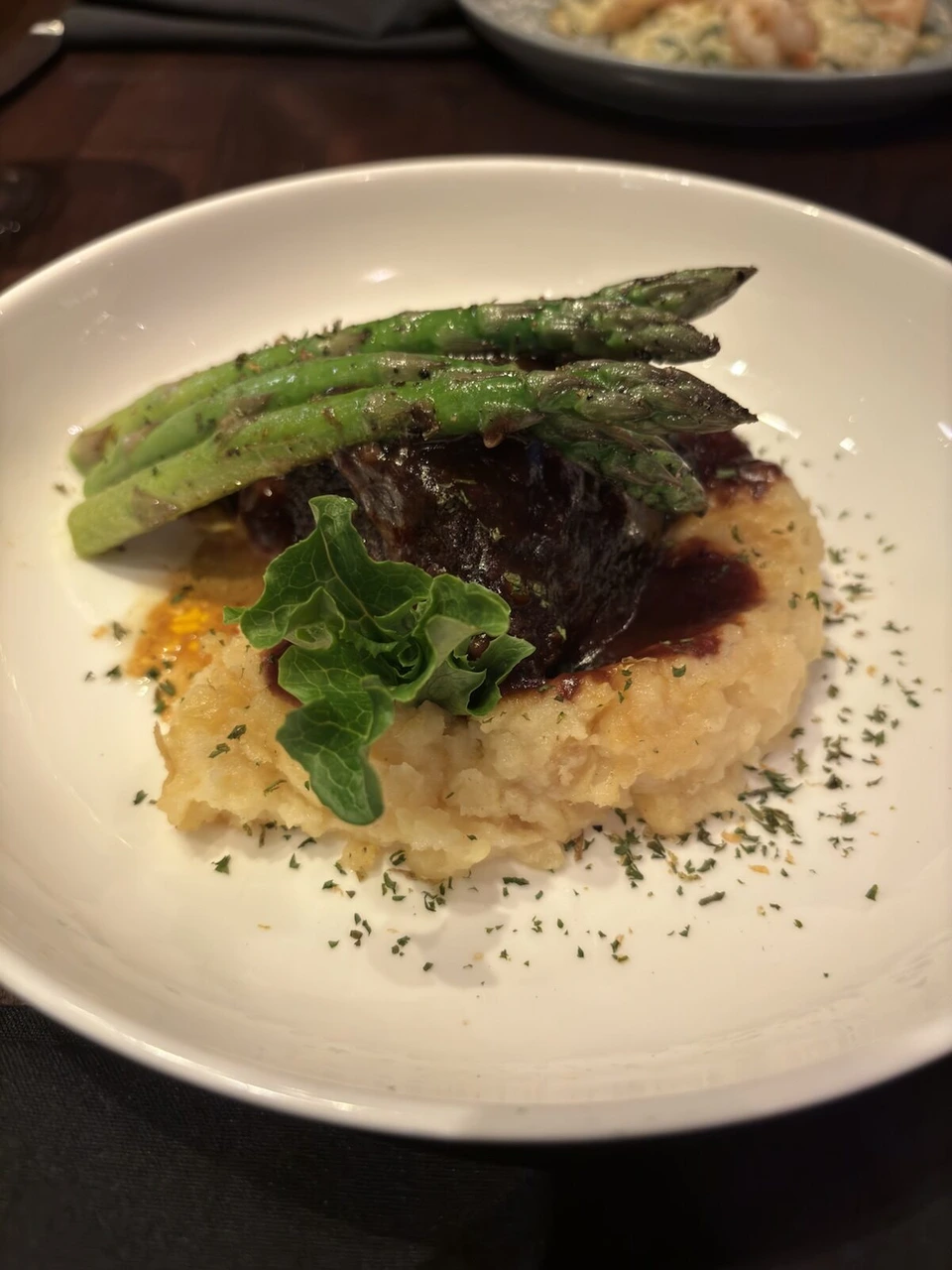 ワシントンDCの夕食。リゾットの上に煮込んだ肉とアスパラガスがのった皿