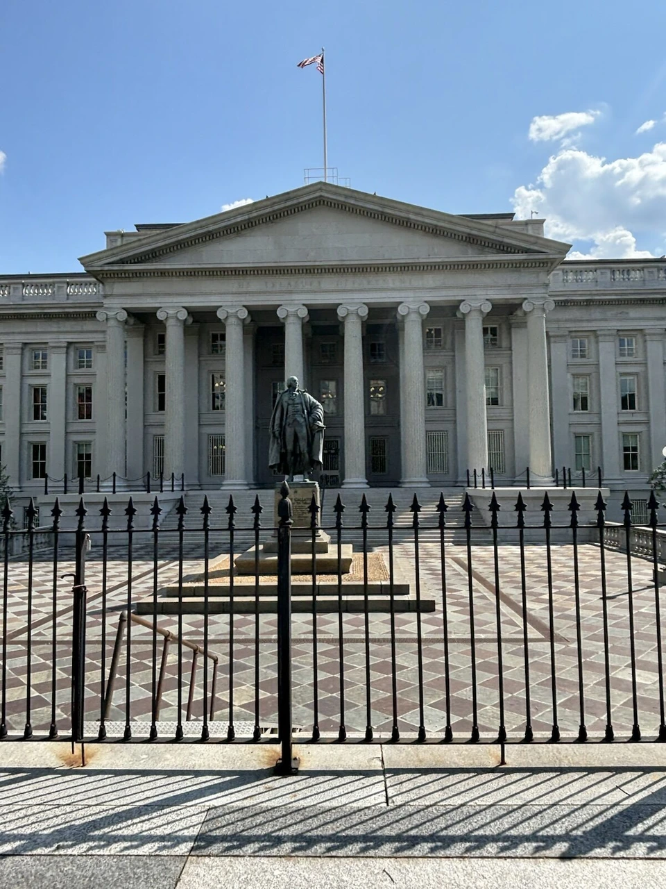 ホワイトハウスの隣、柵の向こうの財務省の建物と正面の銅像