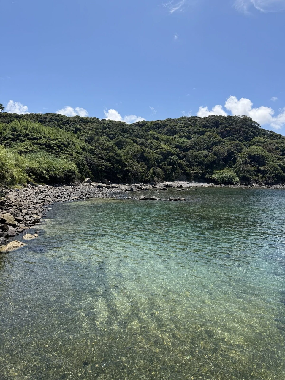 七ツ釜の西側の入り江。緑の山に囲まれ、浅瀬の海水が透明で底の岩まで見える