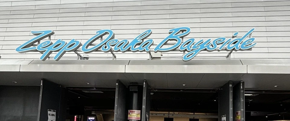 Zepp Osaka Baysideの正面入口。青い筆記体の館名の下で黒い扉が開いていて、扉に再入場禁止の貼り紙