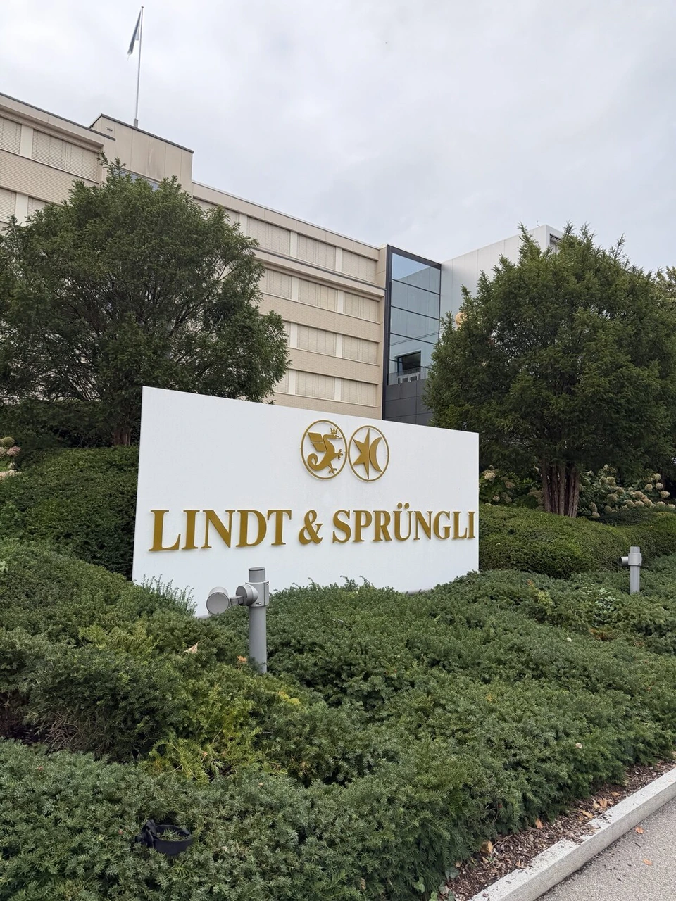 植え込みの中に立つLINDT & SPRÜNGLIの白い看板