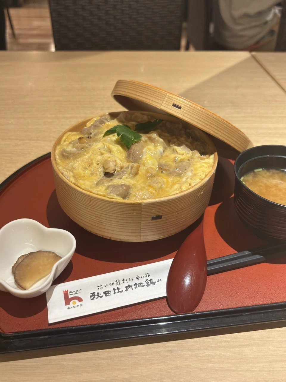 曲げわっぱに入った比内地鶏の親子丼と味噌汁。箸袋に秋田比内地鶏やの文字
