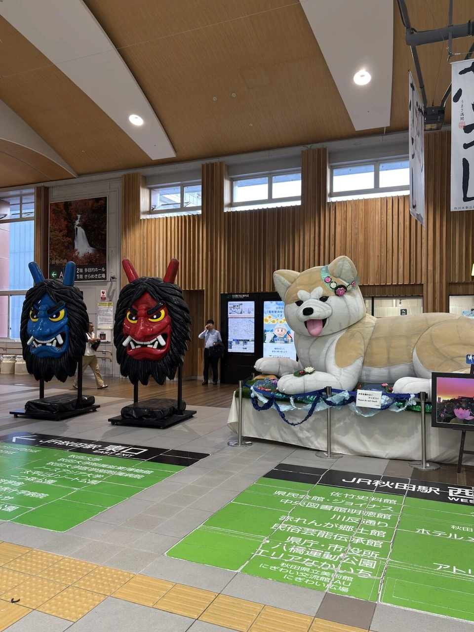 JR秋田駅のコンコース。青と赤のなまはげの面と、大きな秋田犬の像