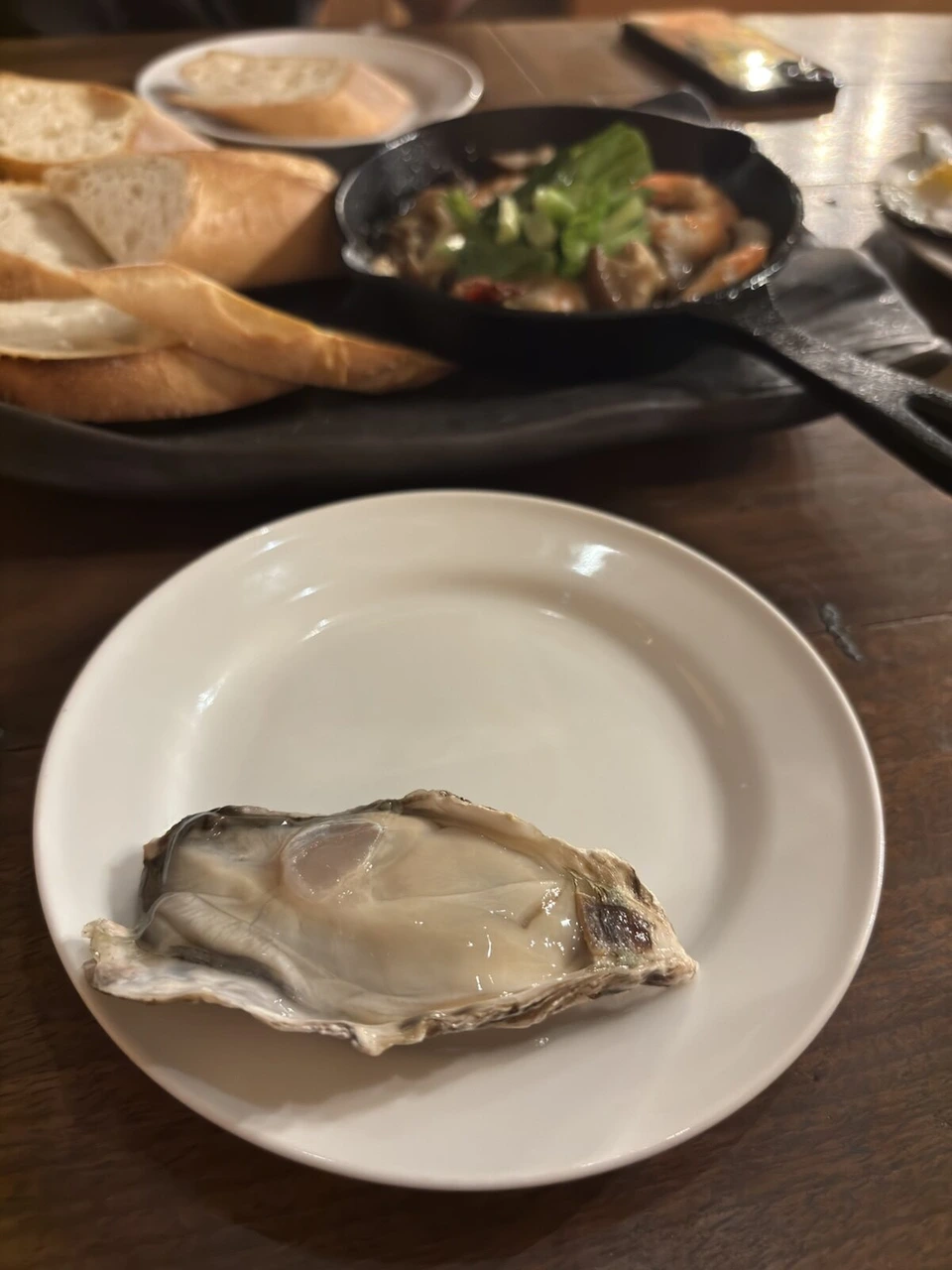 殻付きの牡蠣とアヒージョのような料理、バゲット