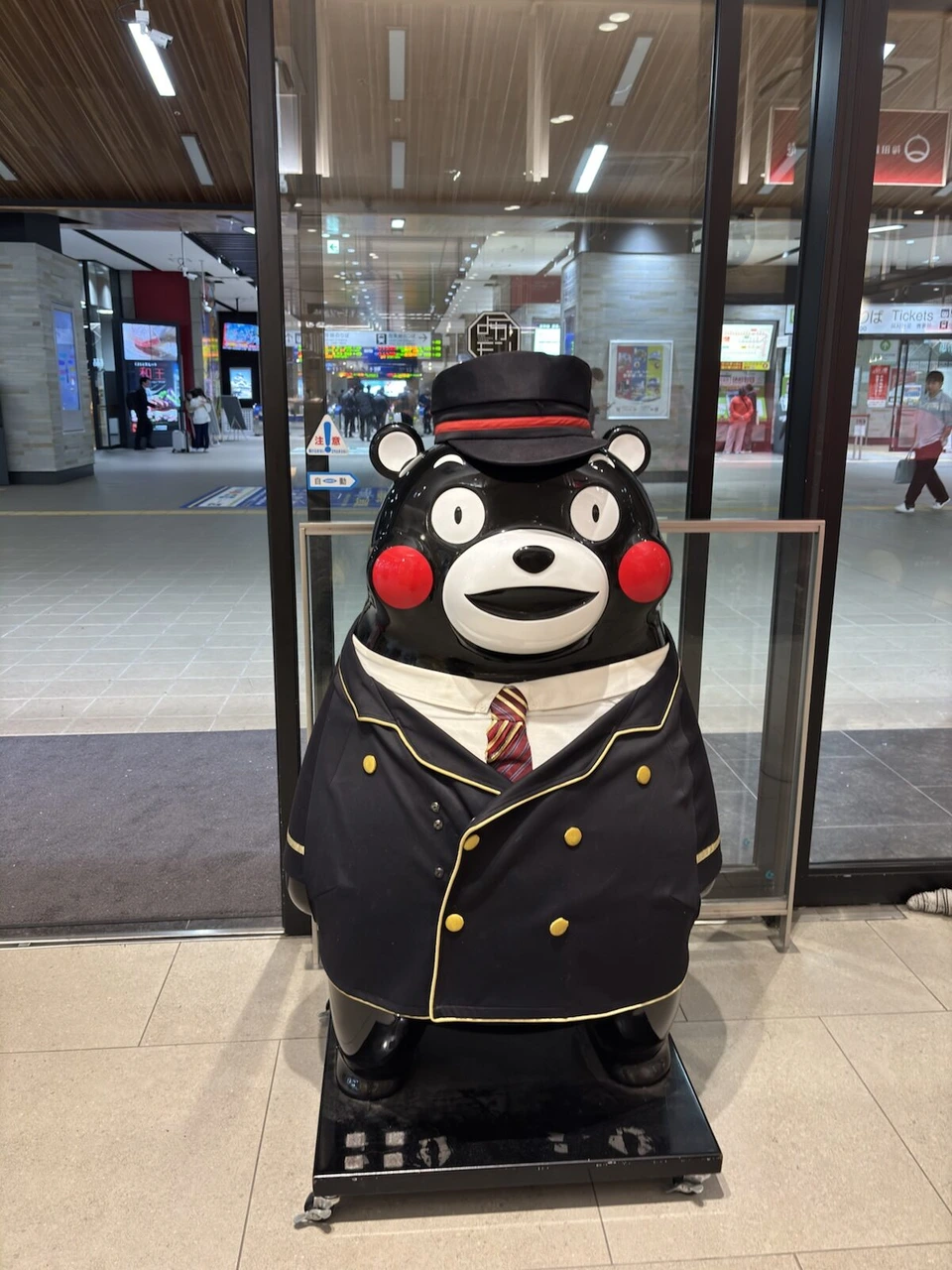 熊本駅の構内に立つ、駅員の制服を着たくまモンの像