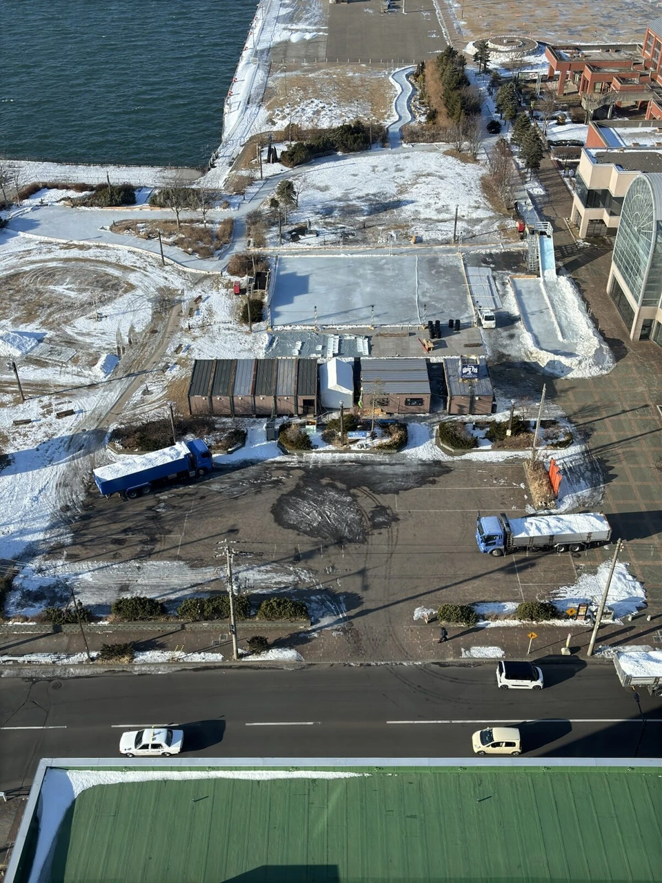 ANAクラウンプラザホテル釧路の窓の真下に見える雪の残る岸壁と倉庫、道路