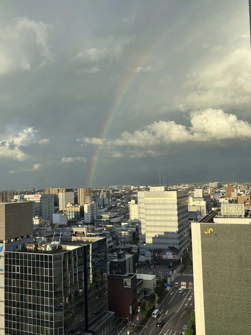 ANAクラウンプラザホテル富山の高層階の窓から見た富山の街と、雲の間にかかる虹