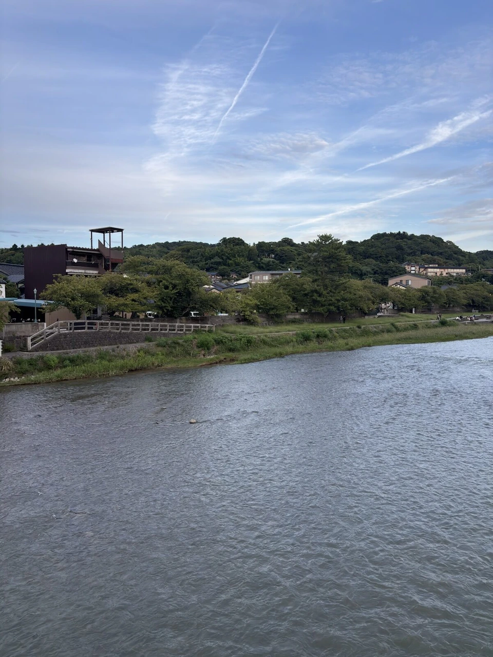夕方の浅野川。川沿いの緑と、遠くの山