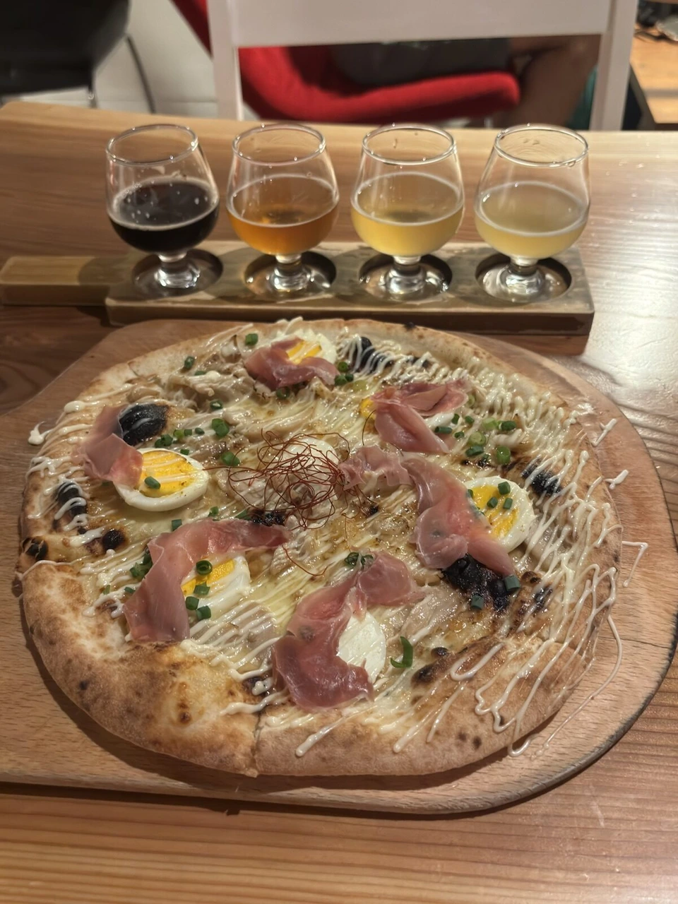 4種類のクラフトビールの飲み比べと、生ハムと卵がのったピザ
