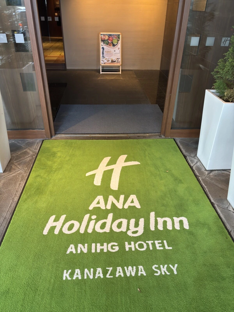 ANAホリデイ・イン金沢スカイの入口の緑色の玄関マット。ANA Holiday Inn KANAZAWA SKYの文字