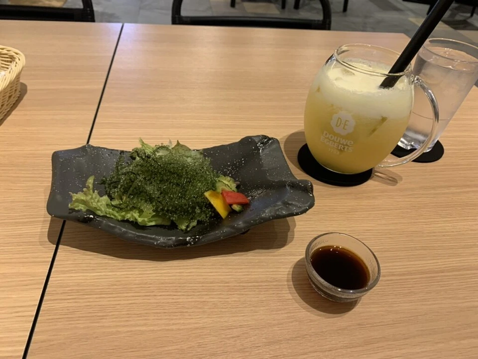 ホテル・アンドルームス那覇ポートの夕食付きプランの海ぶどうと野菜、たれ、黄色い飲み物のグラス