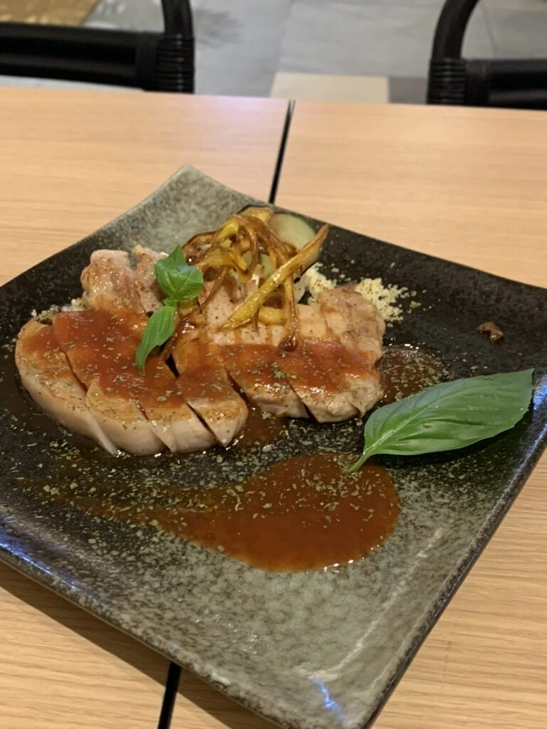 薄切りの肉にトマトソースとバジル、揚げた野菜をのせた一皿