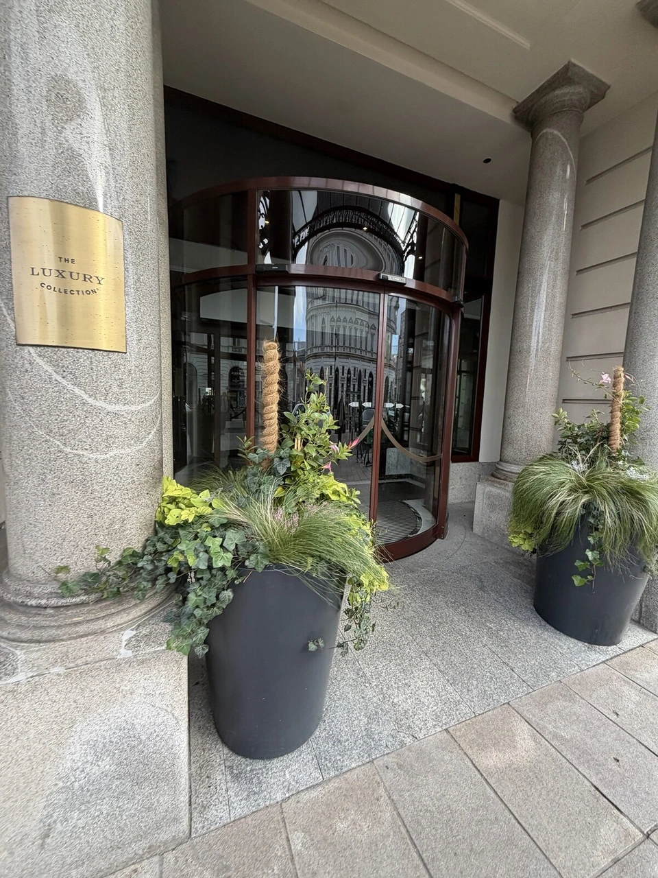 ホテル・ブリストルの入口の回転扉と、金色のTHE LUXURY COLLECTIONのプレート、植木の鉢