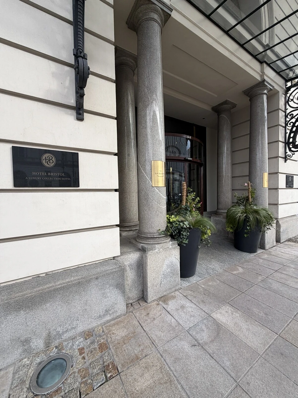 入口の柱に付いた黒いプレート。HOTEL BRISTOL A LUXURY COLLECTION HOTELの文字とHBのマーク