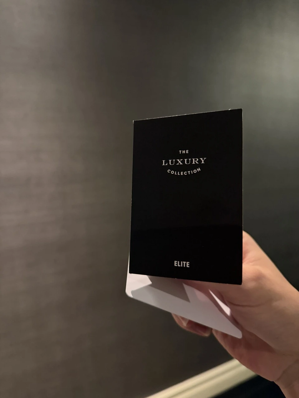 手に持ったTHE LUXURY COLLECTIONの黒いカード。ELITEと書かれている
