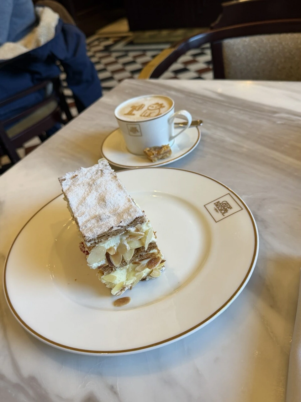 CAFE BRISTOLの皿にのった層になったケーキと、ラテアートのカプチーノ