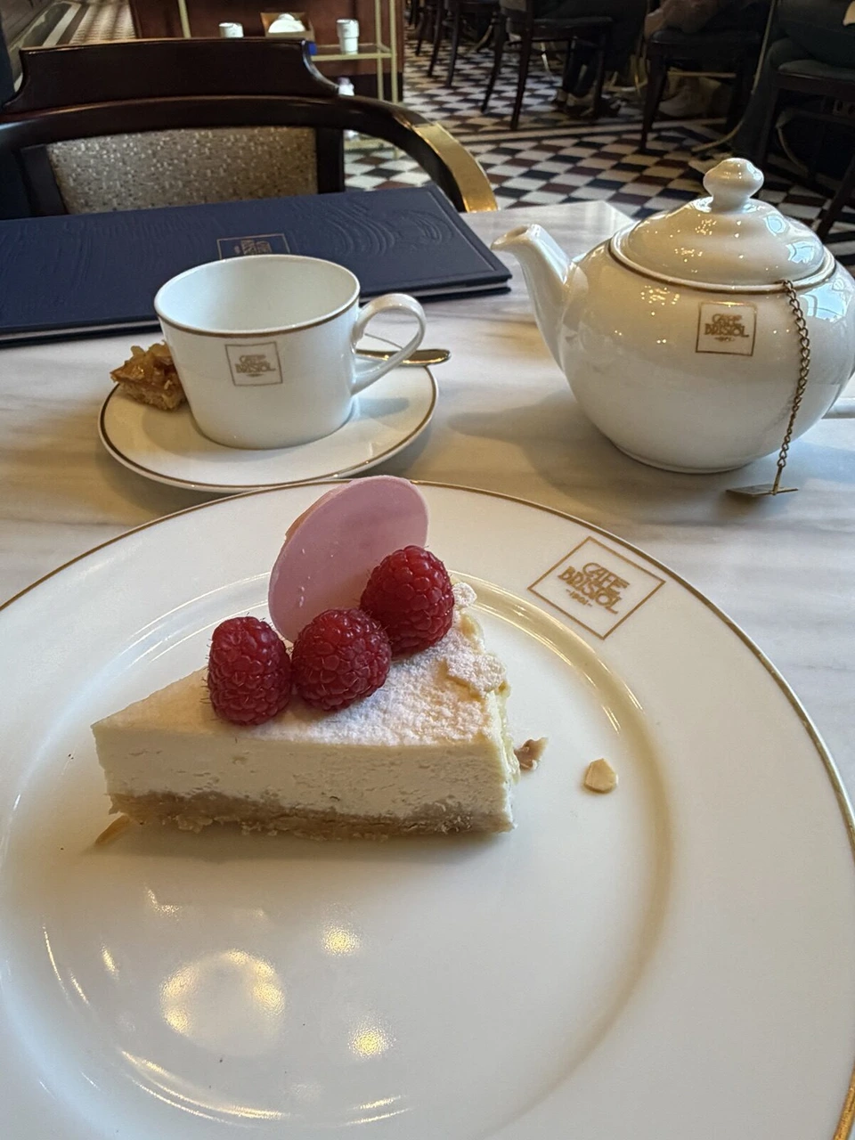 CAFE BRISTOL 1901と書かれた皿のチーズケーキと、紅茶のポット