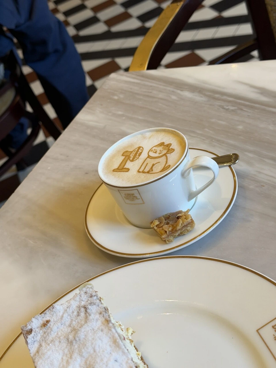 CAFE BRISTOLのカップのカプチーノのラテアートと、小さな焼き菓子