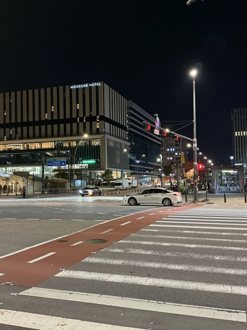 夜の麻谷の交差点。メルキュールホテルの建物と地下鉄の出入口、横断歩道とタクシー