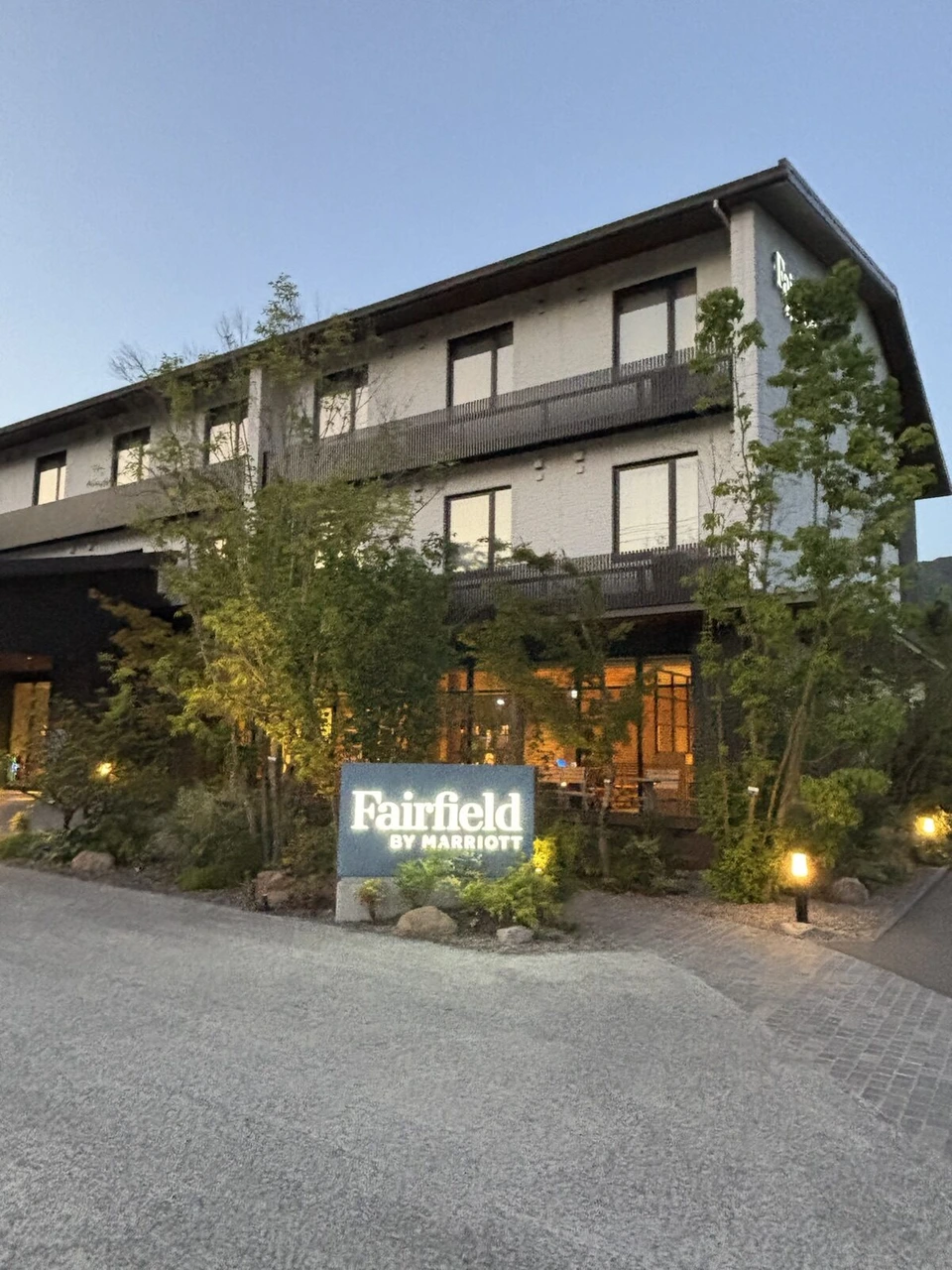 夕暮れのフェアフィールド・バイ・マリオット・広島世羅。白い3階建ての建物の前に光るFairfield BY MARRIOTTの看板