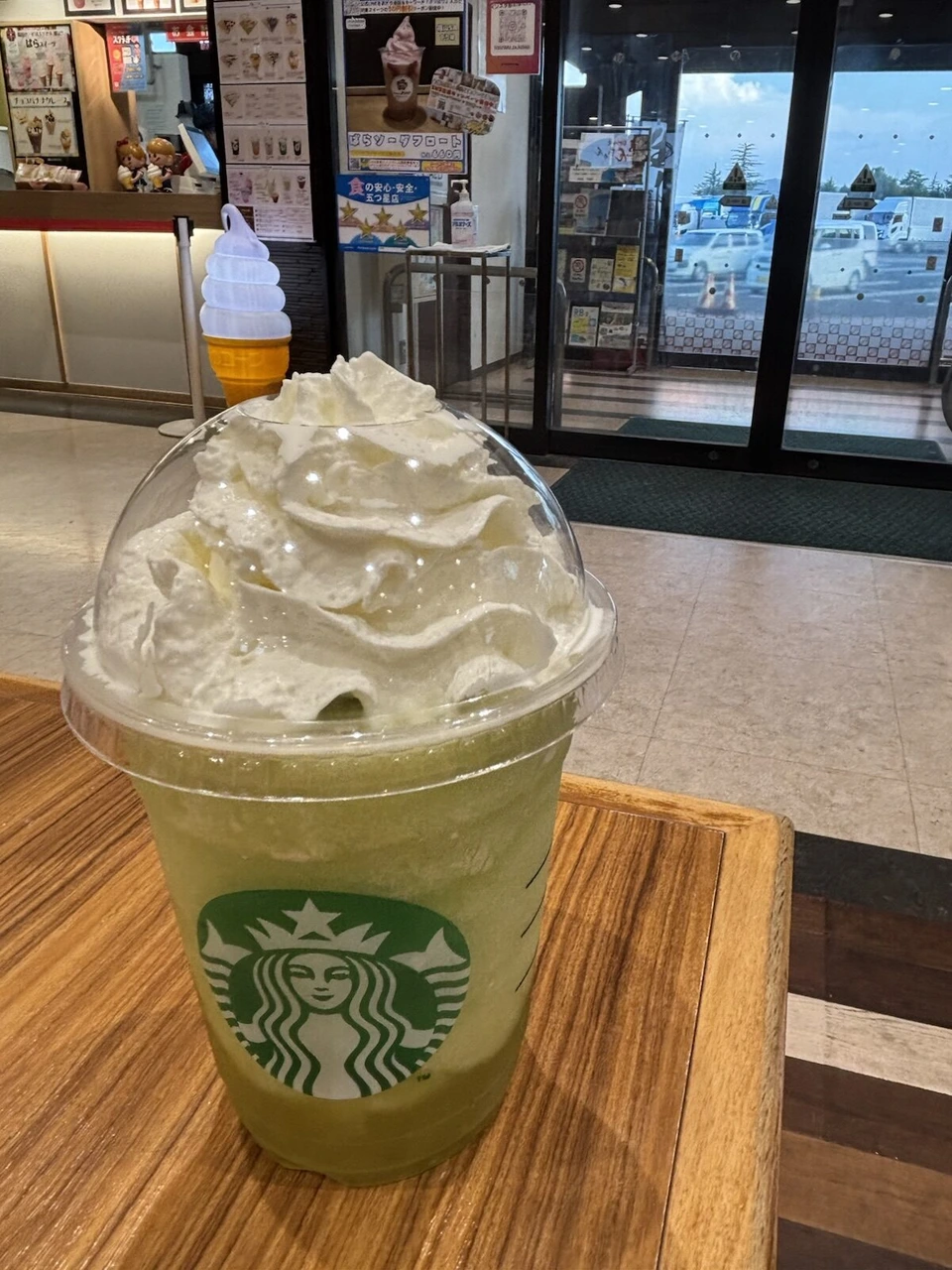 福山サービスエリアのスターバックスの緑色のフラペチーノ。奥にばらソーダフロートのポスター