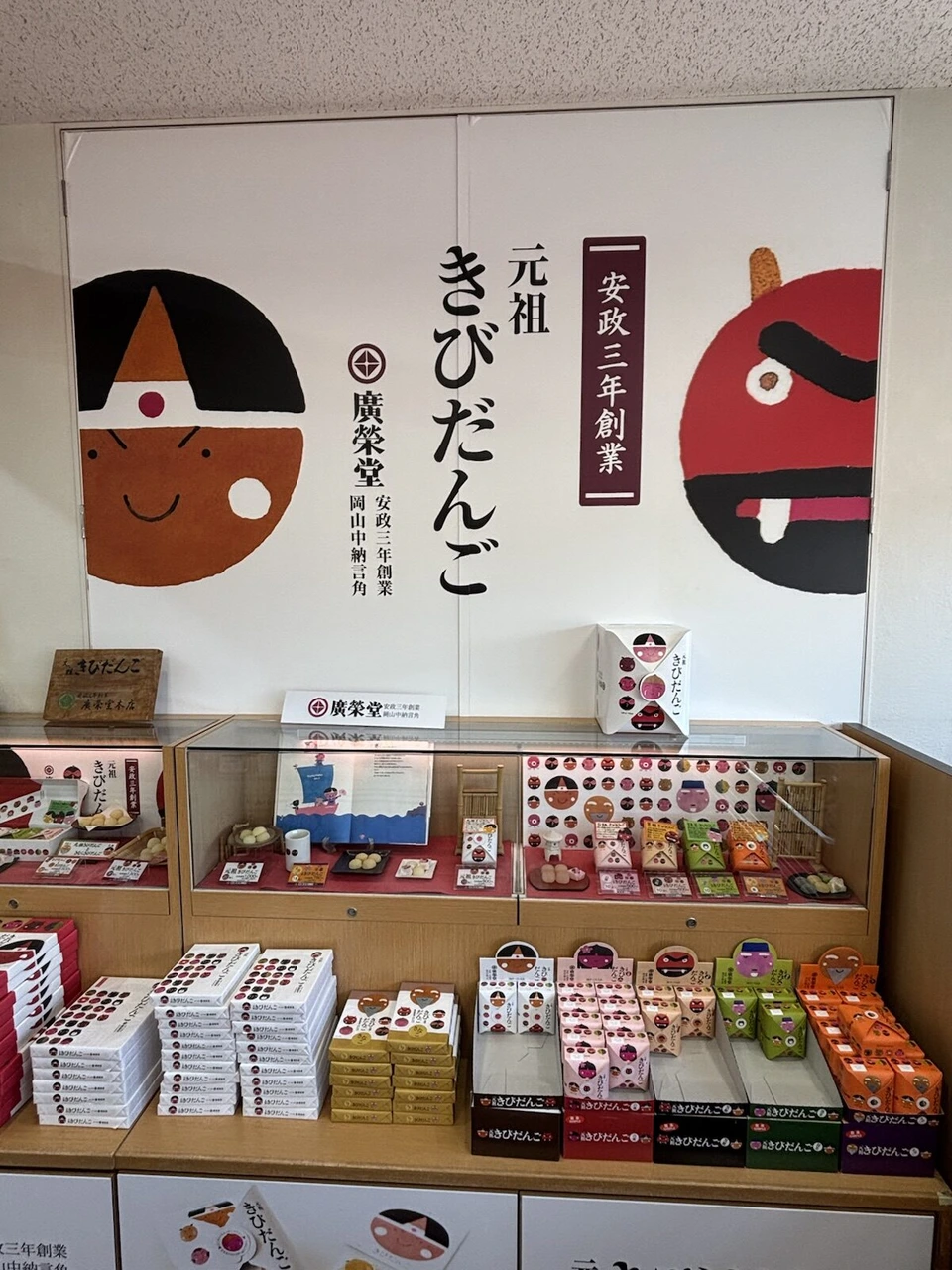 廣榮堂の元祖きびだんごの売り場。桃太郎と鬼の大きな絵の下に箱入りのきびだんごが並ぶ