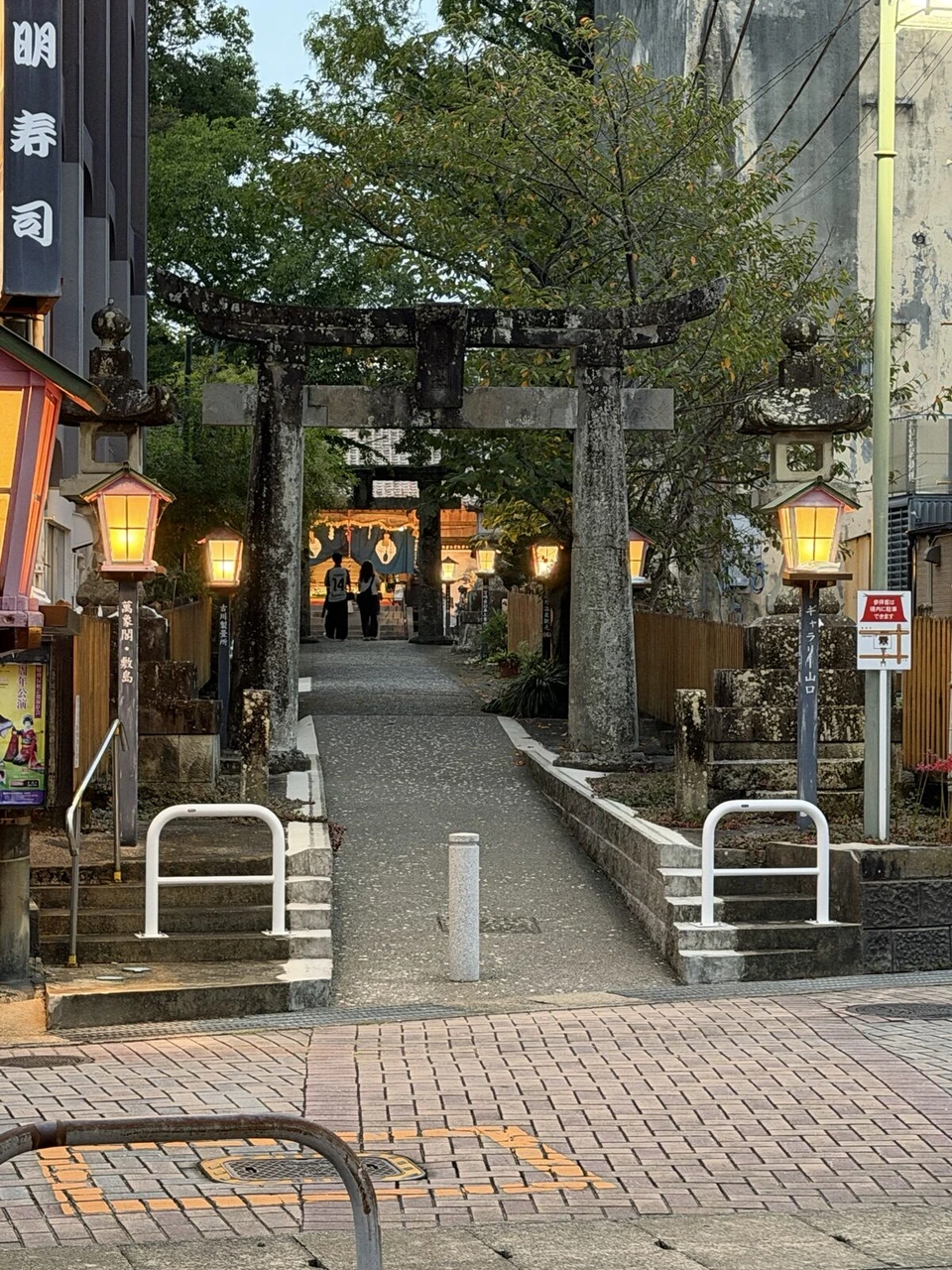 夕方の嬉野温泉街の神社の石の鳥居と参道、両側の灯籠
