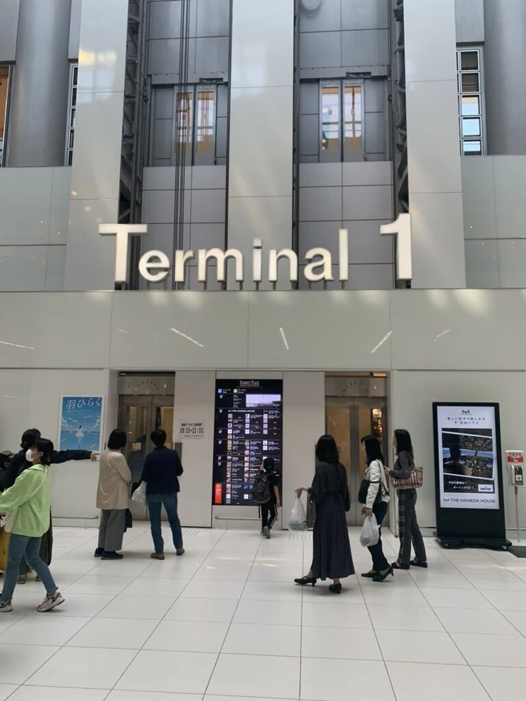 羽田空港第1ターミナルの館内。「Terminal 1」の大きな表示とエスカレーター