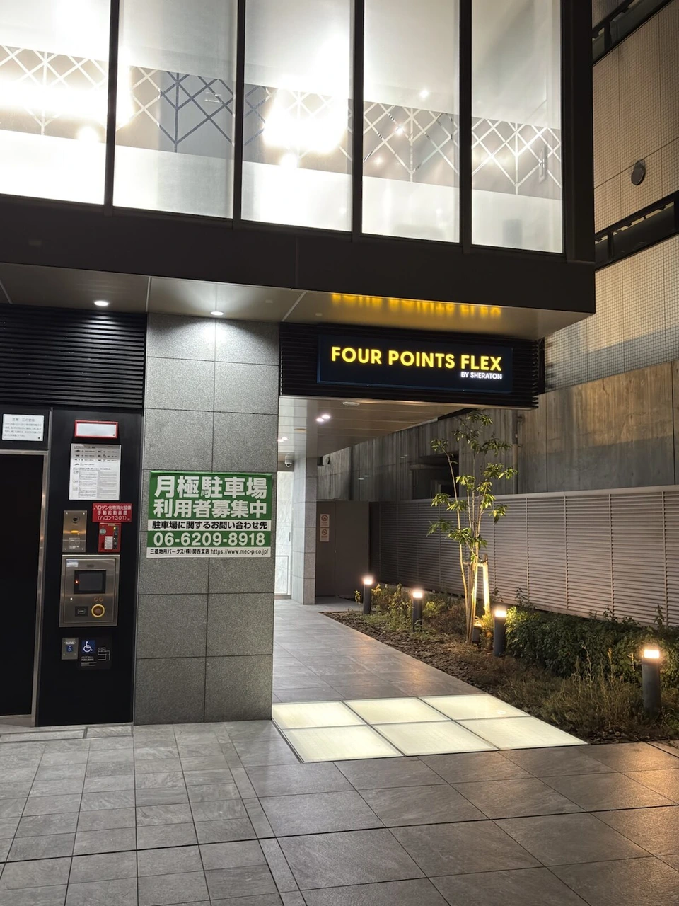 フォーポイント フレックス大阪北浜の入口通路。FOUR POINTS FLEX BY SHERATONの看板と植え込み