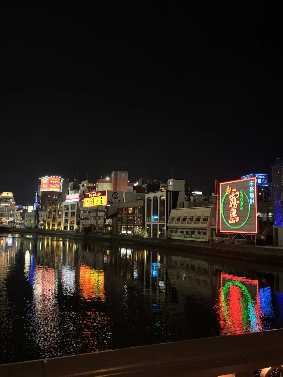 夜の那珂川沿いに並ぶ中洲の看板とネオン