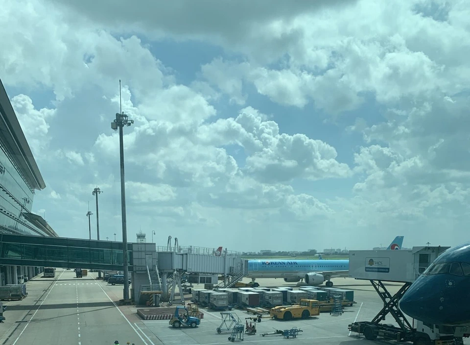 タンソンニャット空港のターミナルの窓から見た駐機場。搭乗橋につながったベトナム航空機と貨物コンテナ