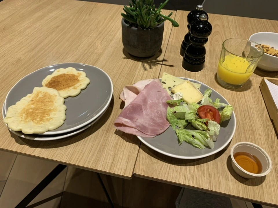 INNSiDE Paris CDGの朝食の皿。小さなパンケーキ、ハム、チーズ、サラダ、オレンジジュース