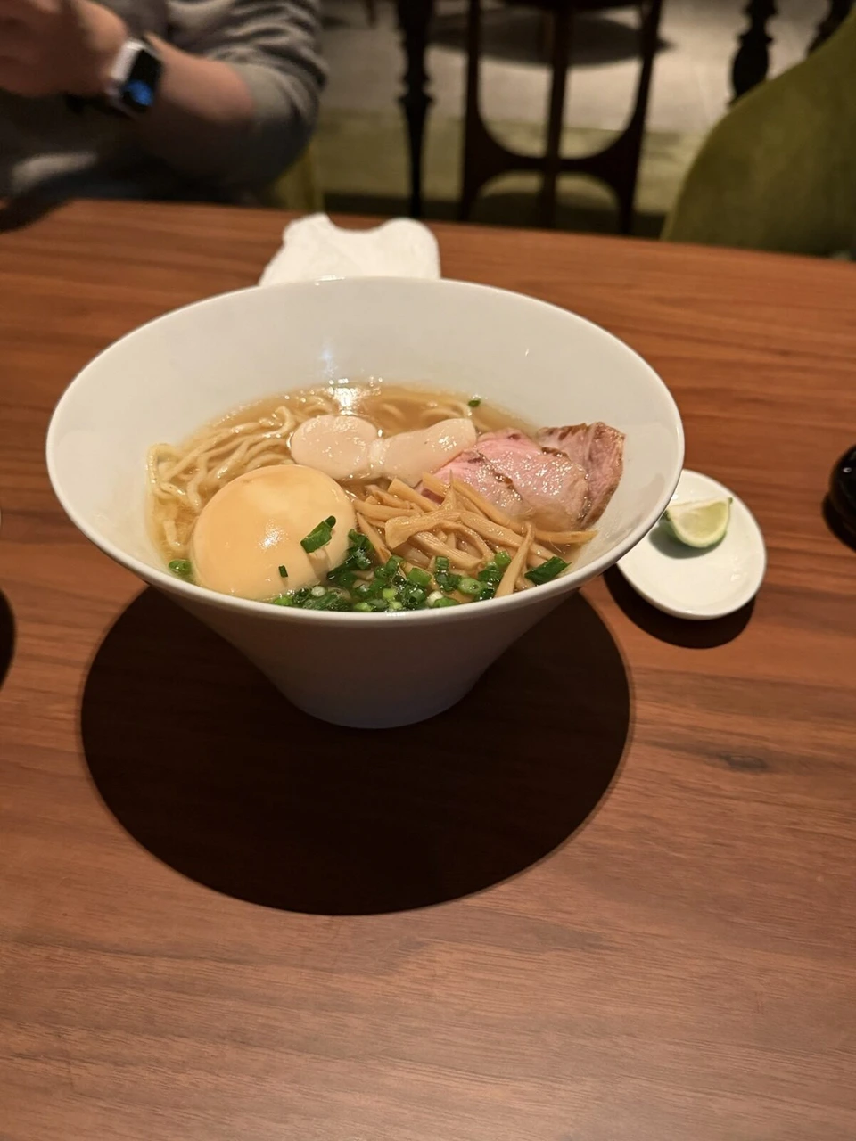 白い器のラーメン。味玉、チャーシュー、ねぎ、すだち
