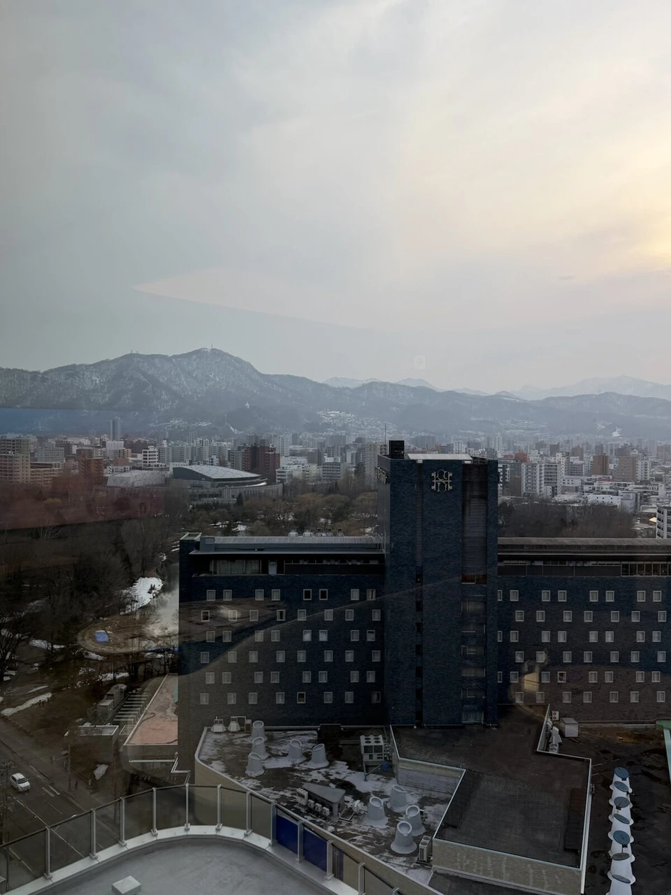 インターコンチネンタル札幌の高層階から見た中島公園側の街並みと、奥に連なる雪の残る山