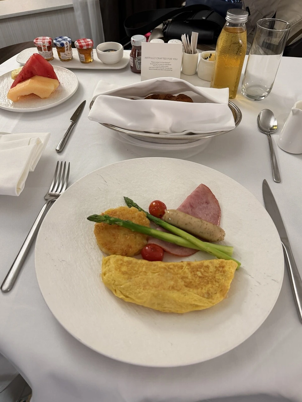JWマリオット・ホテル香港のインルームダイニングの朝食。オムレツ、ハム、ソーセージ、アスパラガス、ハッシュブラウン、フルーツ、パンかご、ジャム3種、アップルジュース