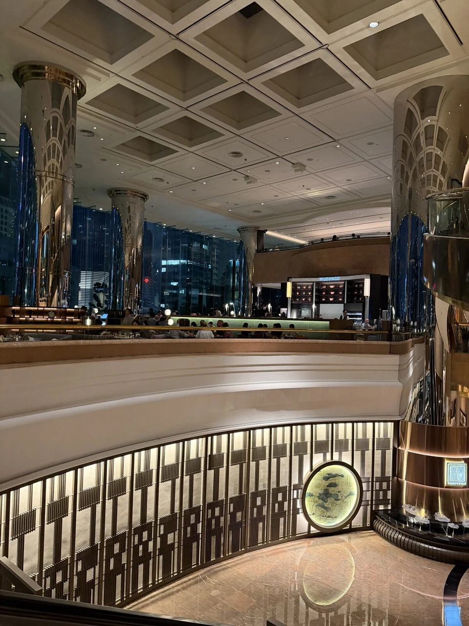 JWマリオット・ホテル香港のロビー階。金属の円柱と格天井、THE LOUNGEの表示、下の階の中国料理店の円窓
