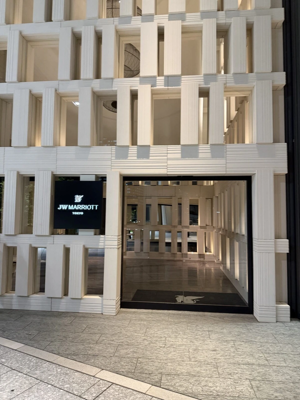 白い格子状の外壁にJW MARRIOTT TOKYOの黒いサインがあるホテル1階の入口