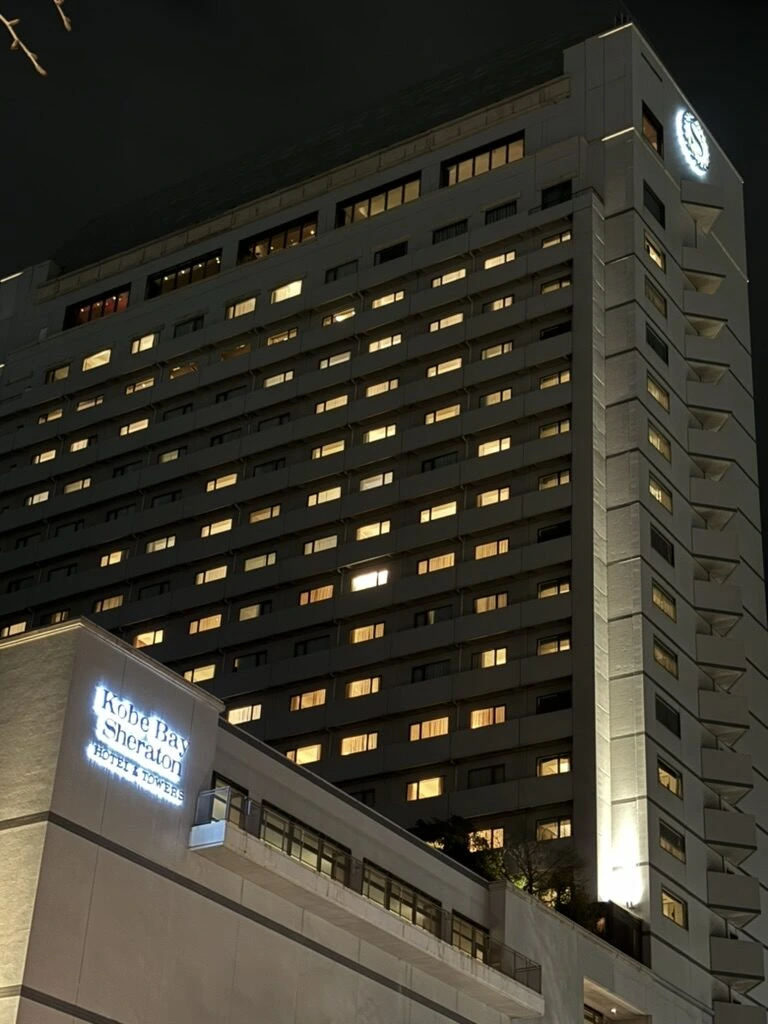 夜の神戸ベイシェラトンのタワー。客室の窓に明かり、低層部にホテルのロゴ