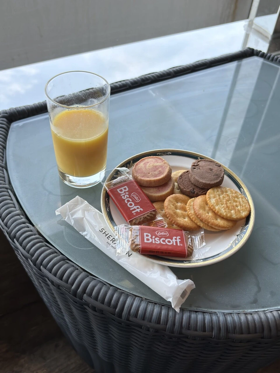 プリファードダブルの窓際のガラスのテーブルにオレンジジュースとクッキー、SHERATONのおしぼり