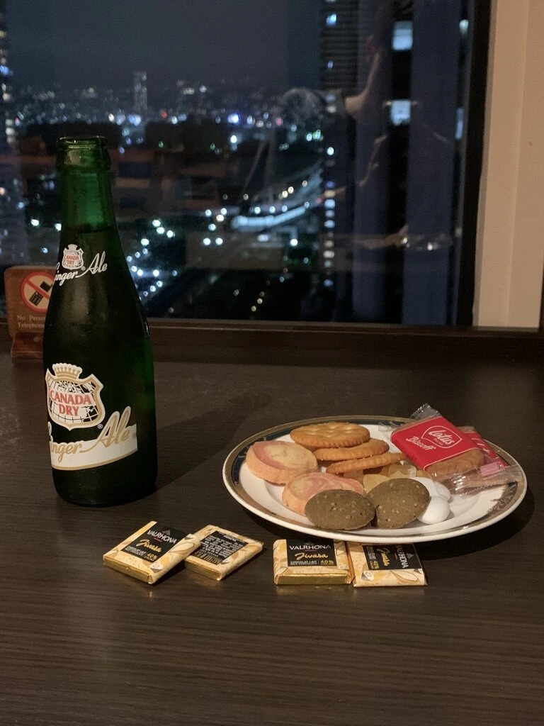 夜景の見える窓際のテーブルにジンジャーエールの瓶とクッキーの皿