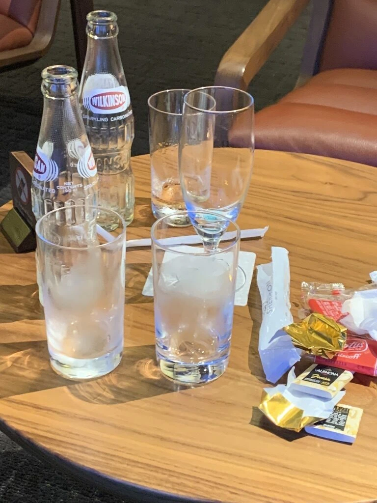クラブラウンジのテーブルに炭酸水の瓶、グラス、個包装のお菓子