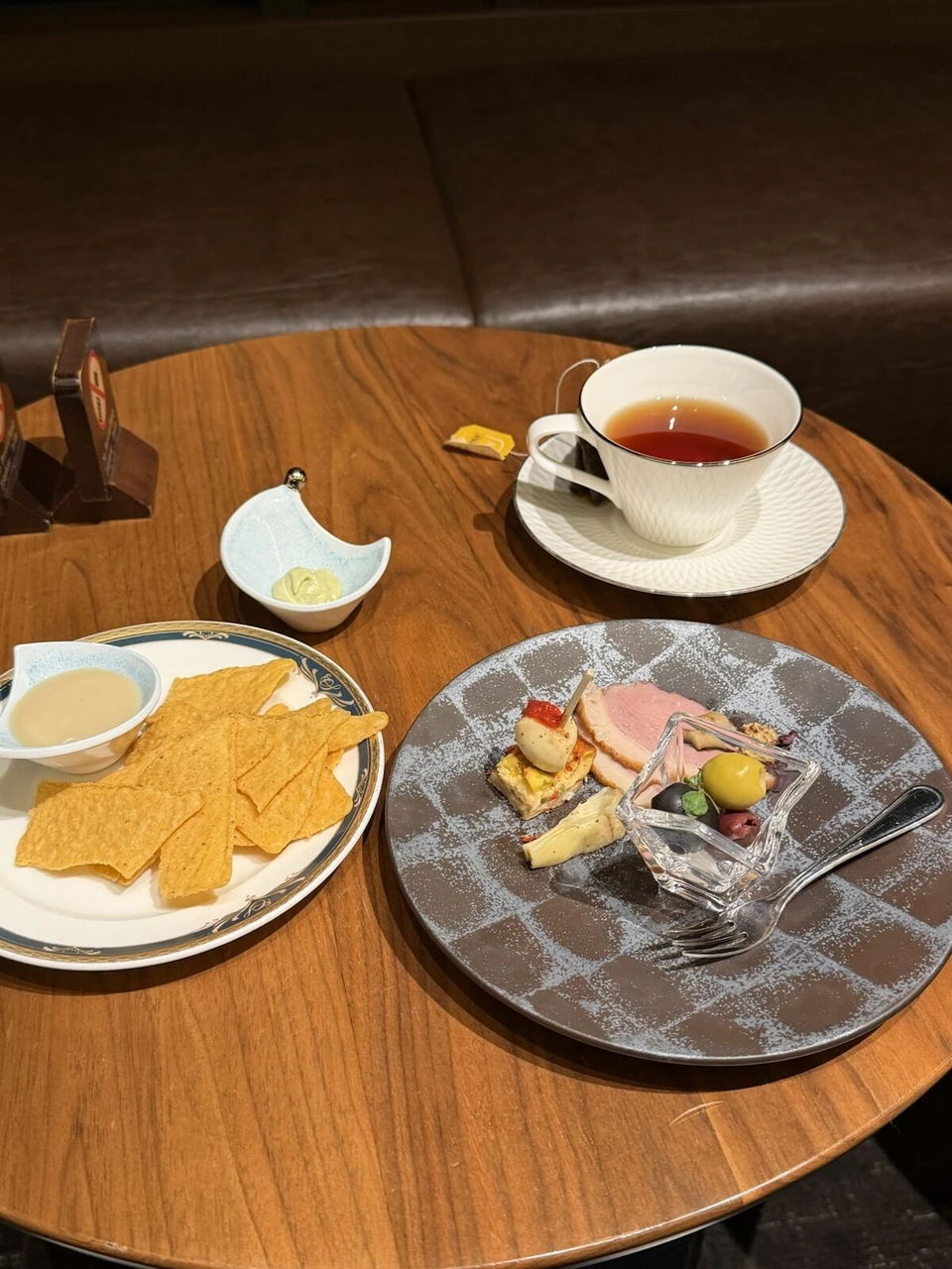 紅茶とチップス、前菜の皿が乗った丸テーブル