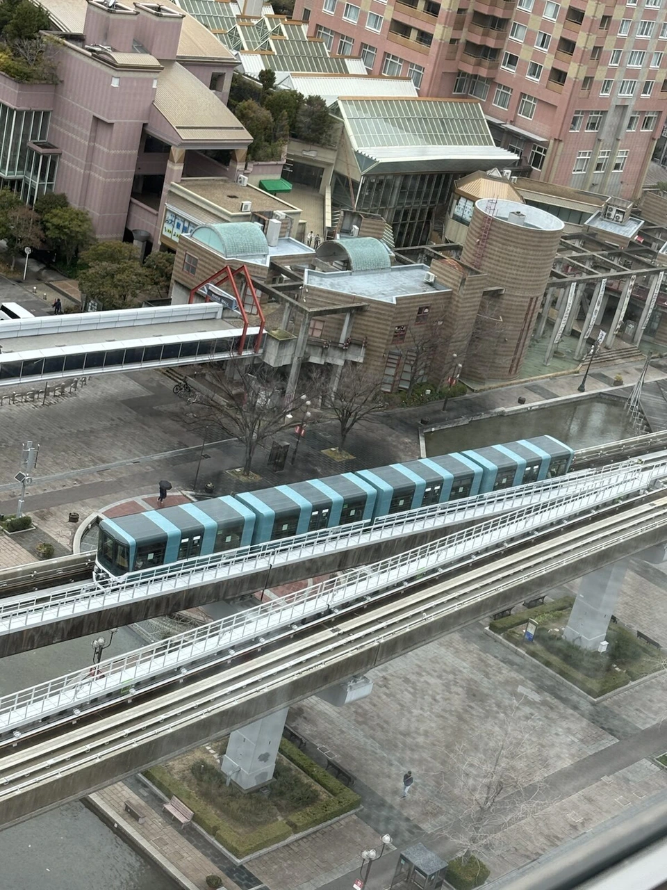 ホテルの上の階から見下ろした、高架を走る水色の六甲ライナーの車両と六甲アイランドの建物