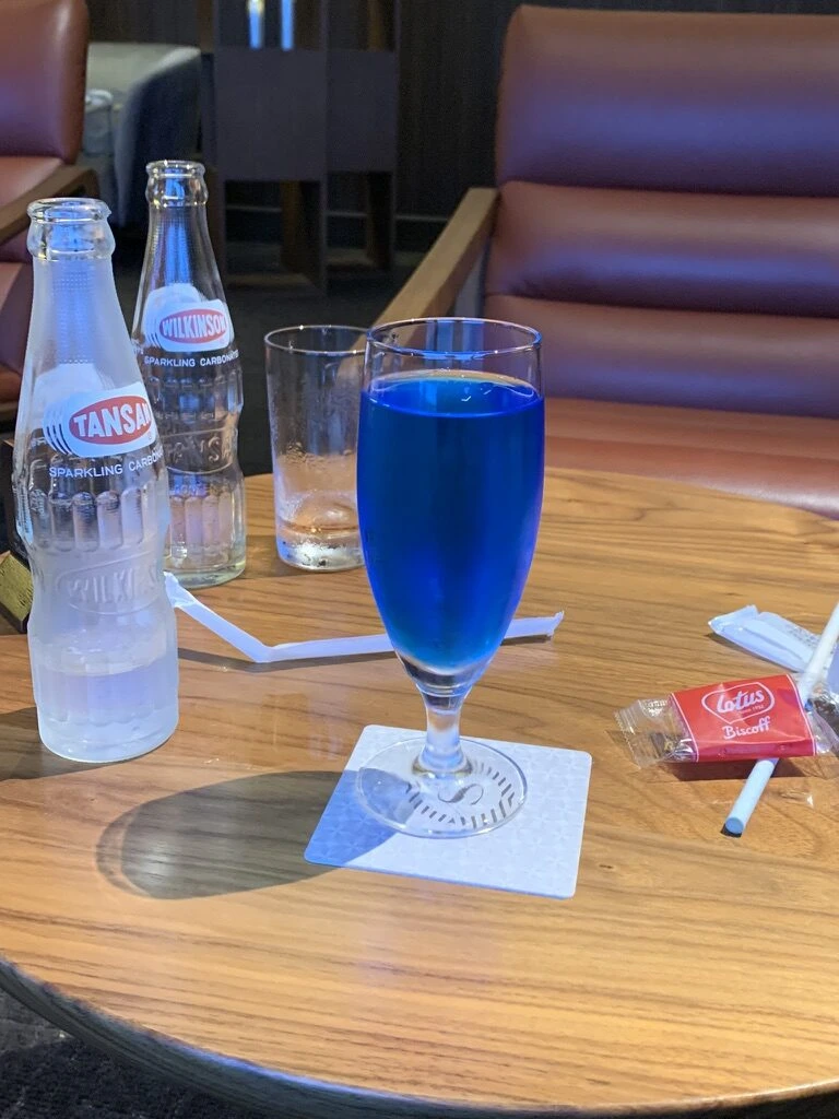 クラブラウンジの丸テーブルに青いドリンクと炭酸水の瓶